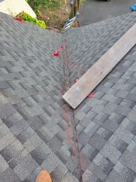 A person is standing on a roof with a piece of wood on it.