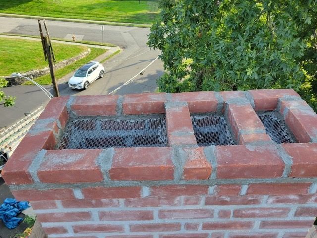 A car is driving down a street next to a brick chimney.