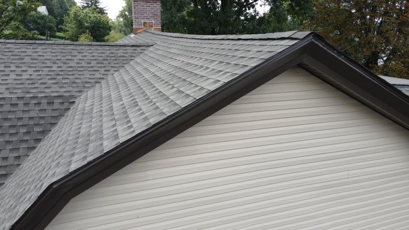 A white house with a gray roof and a brown trim.