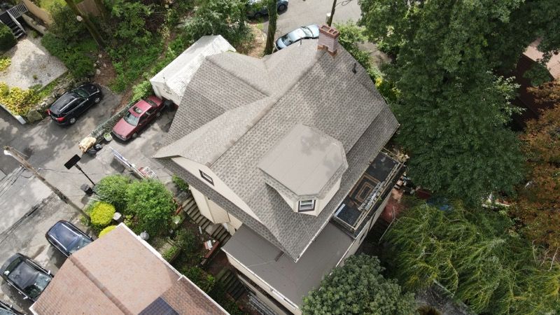 An aerial view of a house in a residential area surrounded by trees.