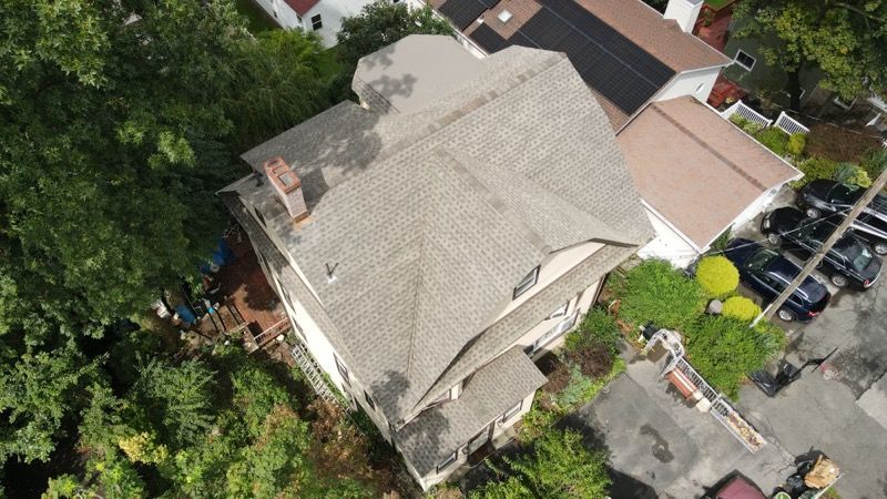 An aerial view of a house with a roof that is surrounded by trees.