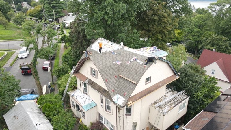 An aerial view of a house being remodeled with workers on the roof.