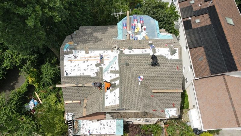 An aerial view of a house being remodeled with workers on the roof.