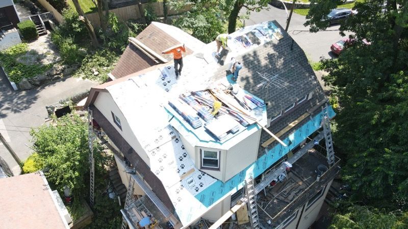 An aerial view of a house under construction with workers on the roof.