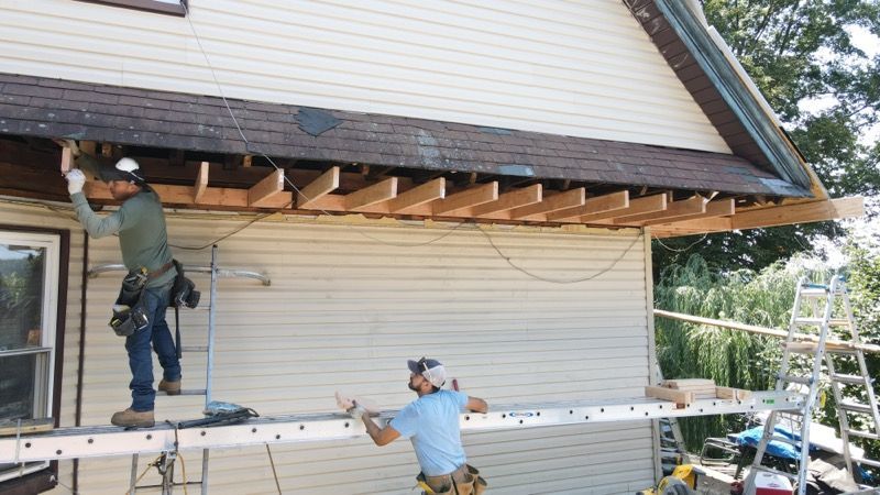 Two men are working on the roof of a house.