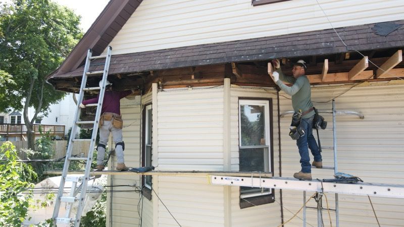 Two men are working on the side of a house