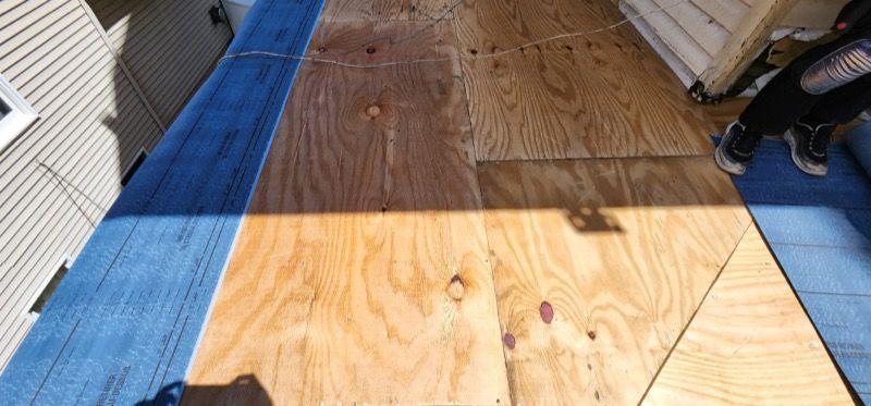 A person is standing on a wooden floor next to a blue tarp.