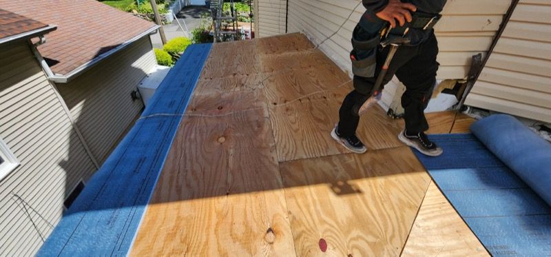 A man is standing on a roof with a hammer.