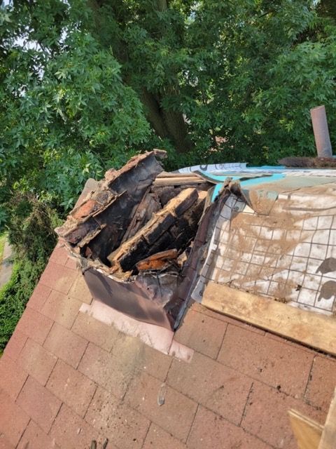 A pile of wood is sitting on top of a brick roof.