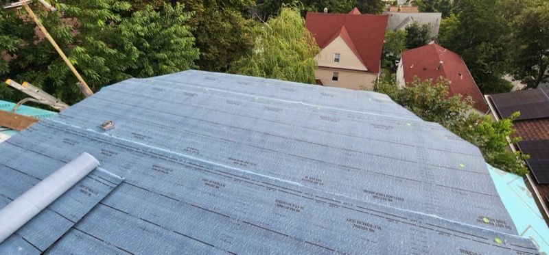 A roof is being installed on a house with a lot of trees in the background.