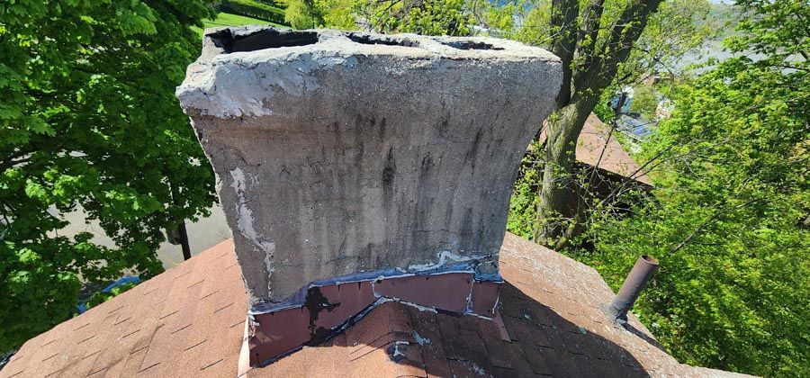 A chimney is sitting on top of a roof with trees in the background.