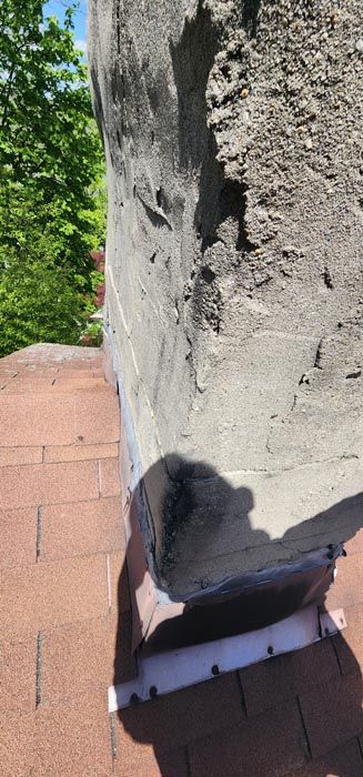 A large rock is sitting on top of a brick roof.