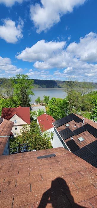 A person is taking a picture of a lake from the roof of a house.