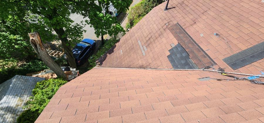 A car is parked on the side of a roof next to a tree.