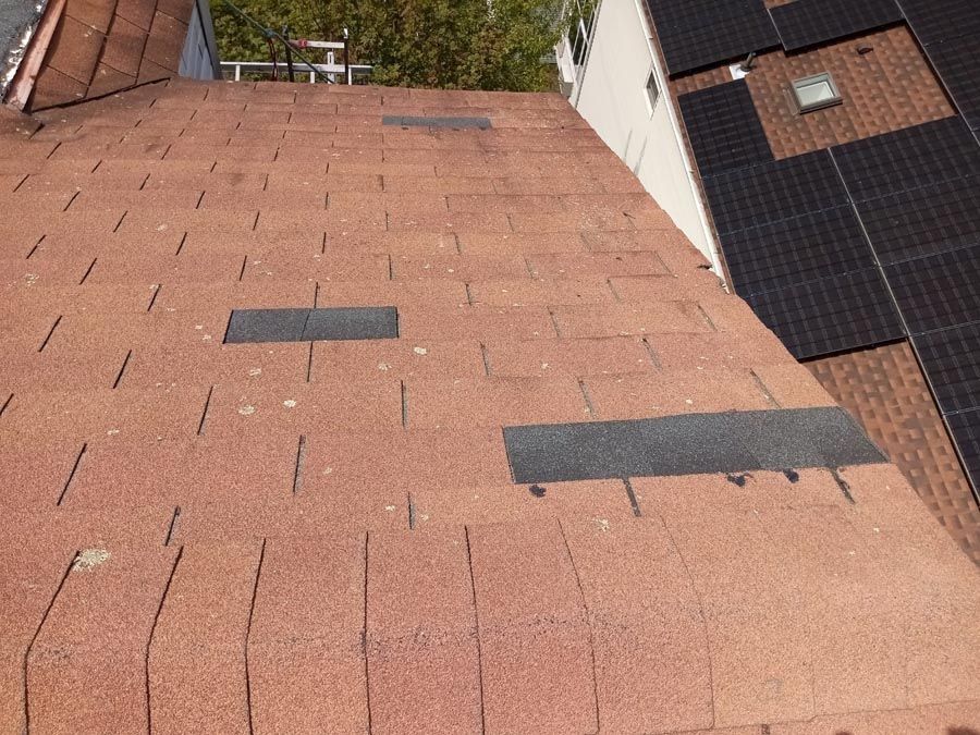 A roof with a lot of shingles and solar panels on it.