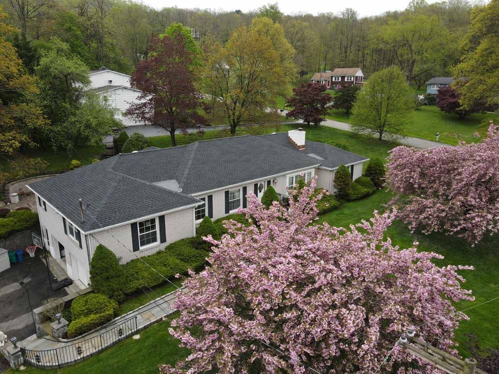 An aerial view of a house with a cherry blossom tree in front of it.