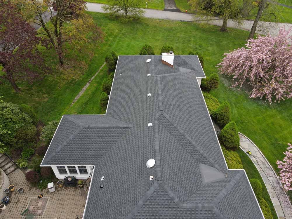 An aerial view of a large house with a roof that is covered in shingles.