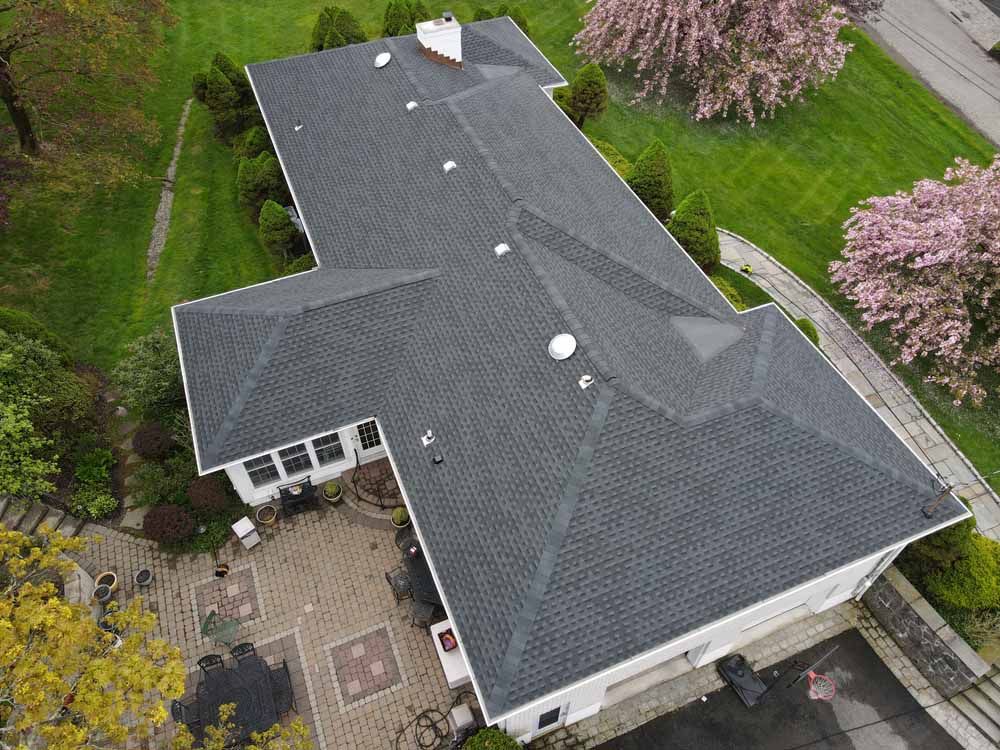 An aerial view of a large house with a black roof and a patio.