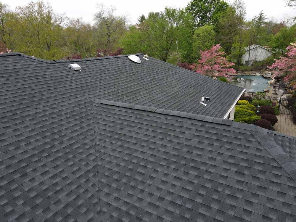 An aerial view of a black roof with a pool in the background.