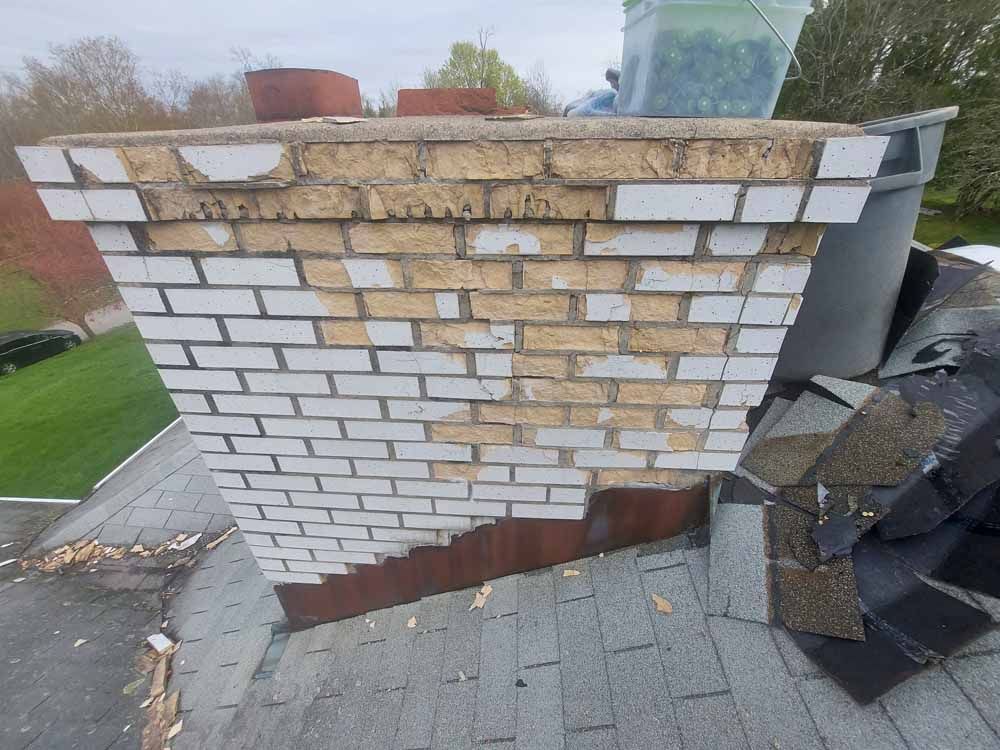 A brick chimney is sitting on top of a roof.