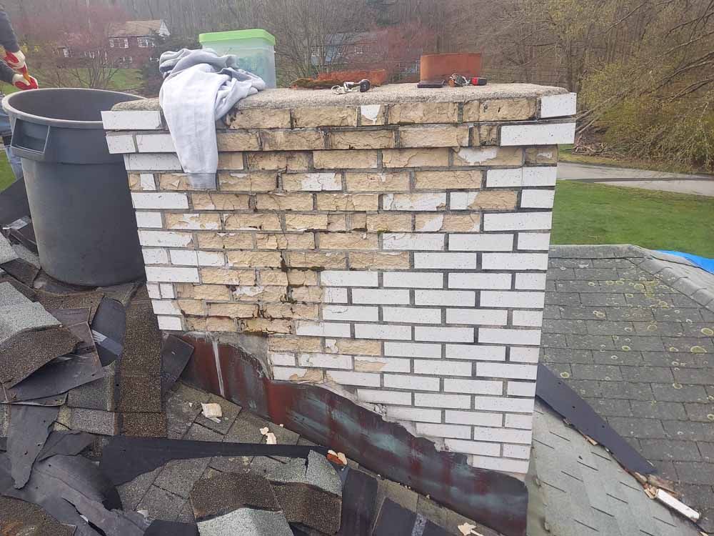 A white brick chimney is sitting on top of a roof.