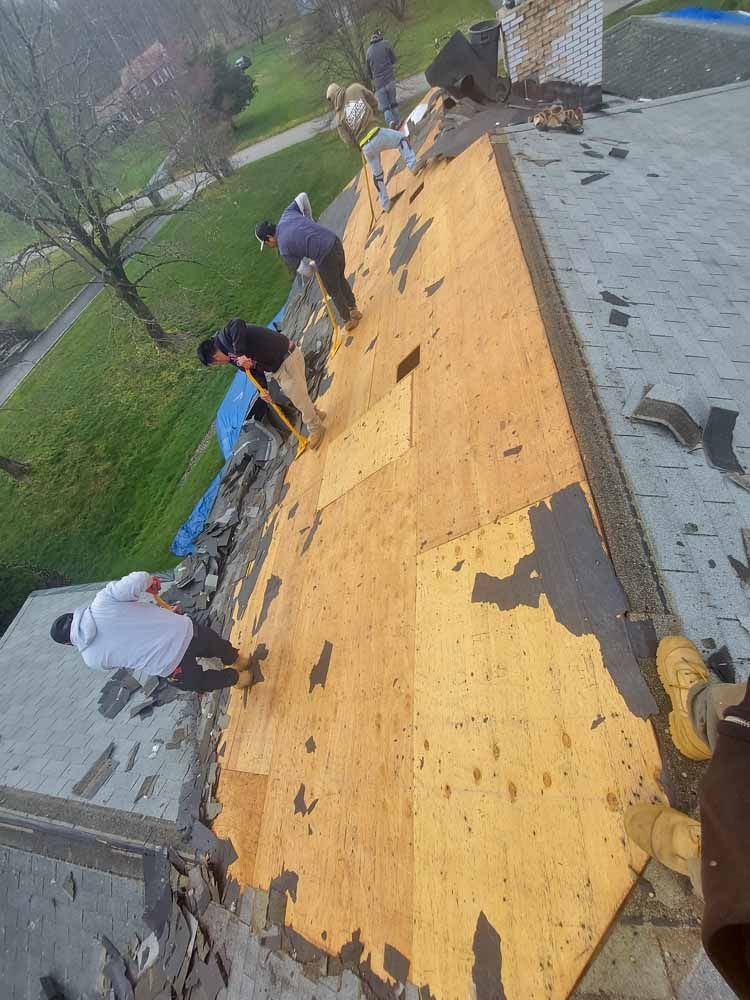 A group of people are working on the roof of a house.