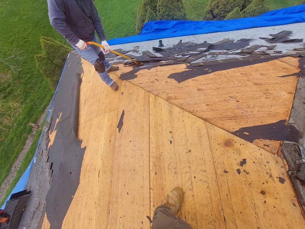 A man is standing on top of a wooden roof.