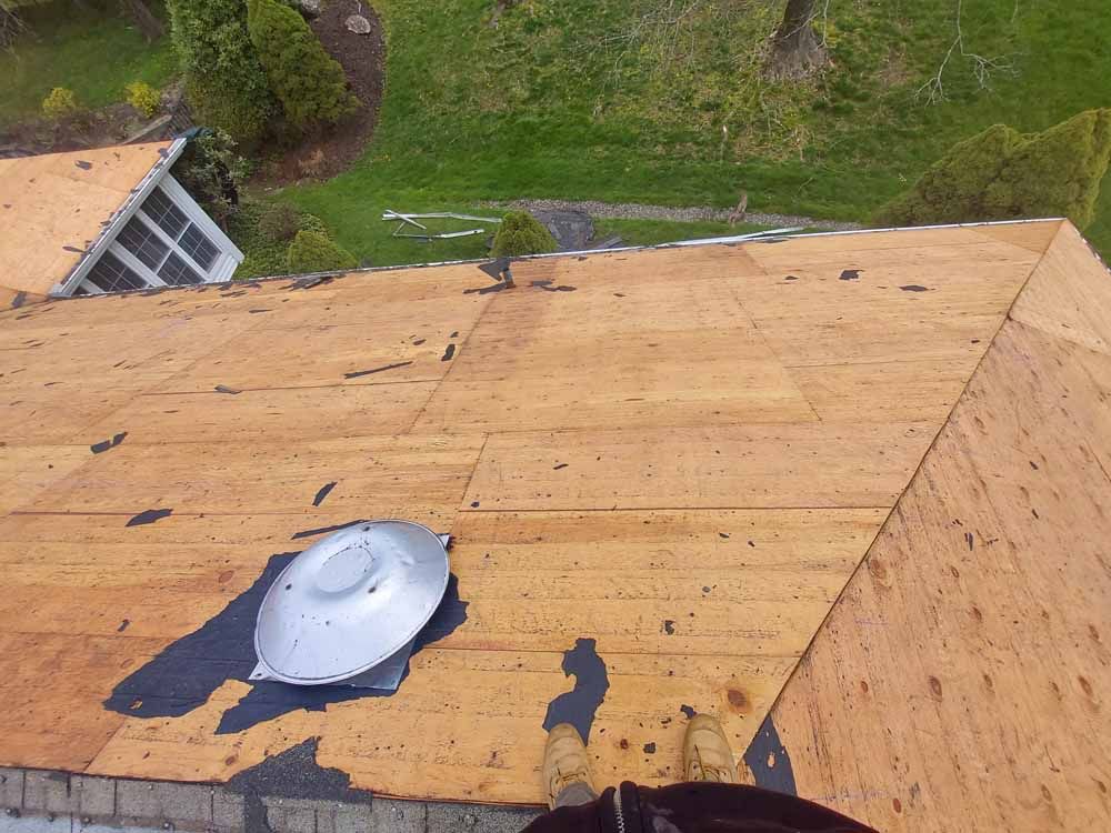 The roof of a house is being repaired and has a skylight on it.