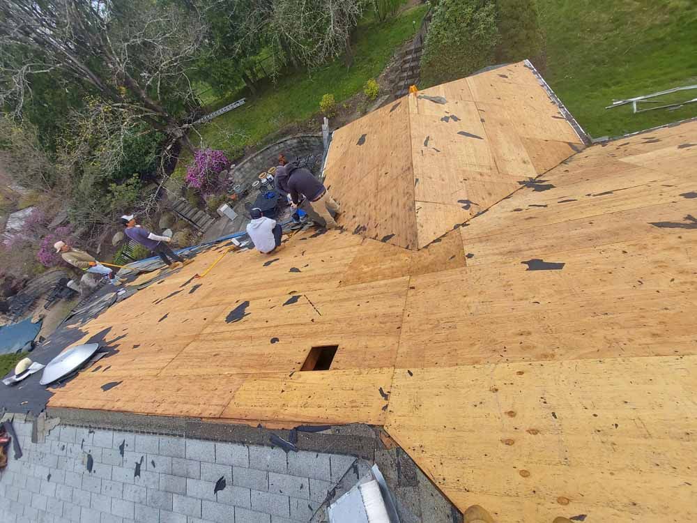 A group of people are working on the roof of a house.