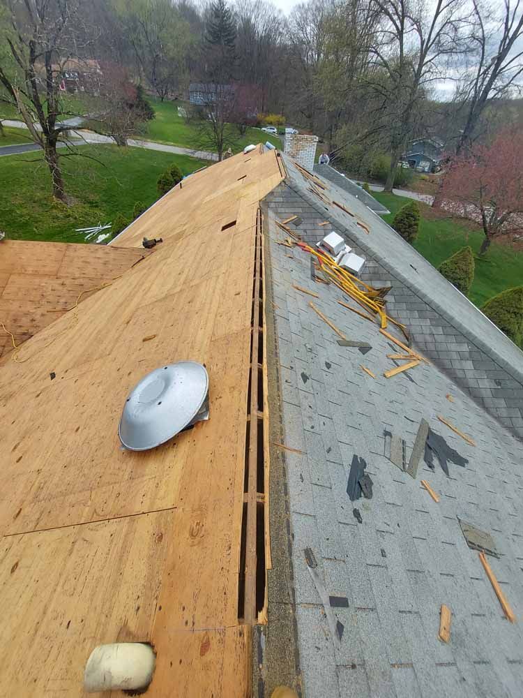 The roof of a house is being remodeled and a satellite dish is sitting on top of it.