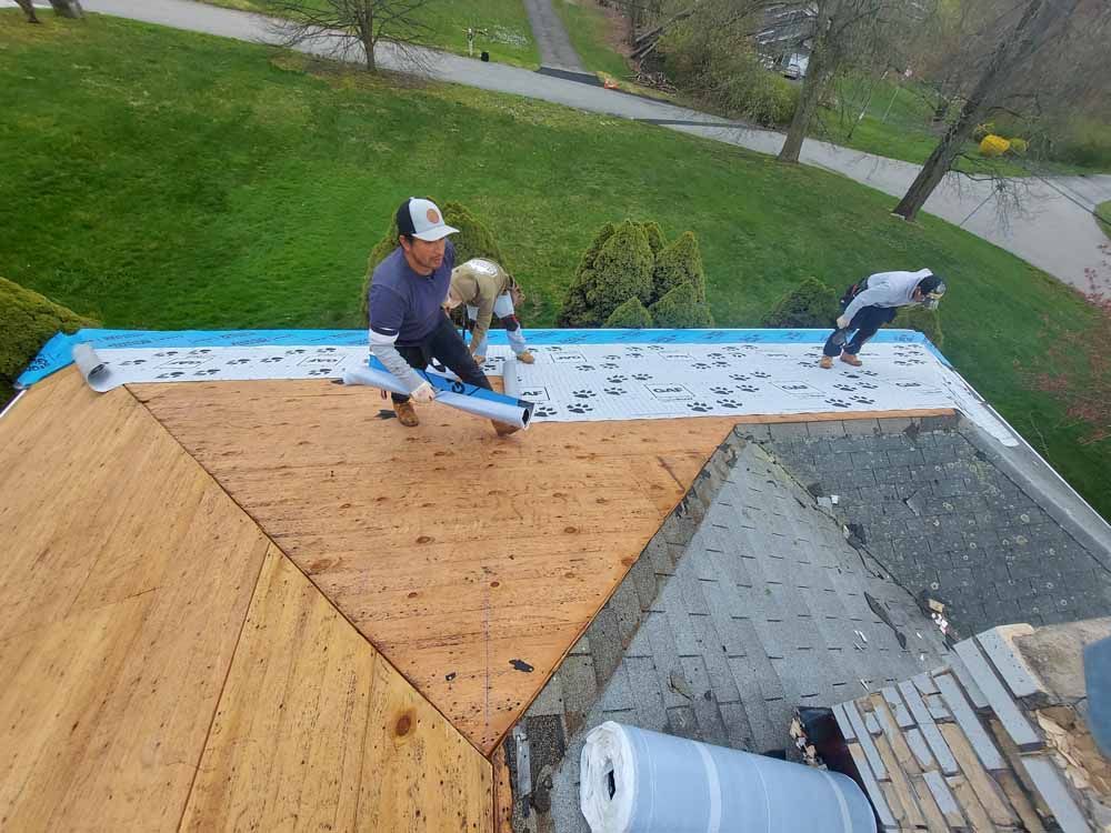 Two men are working on the roof of a house.