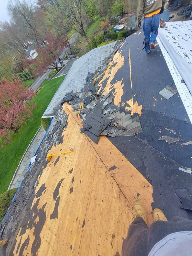 A man is standing on top of a roof that is being repaired.