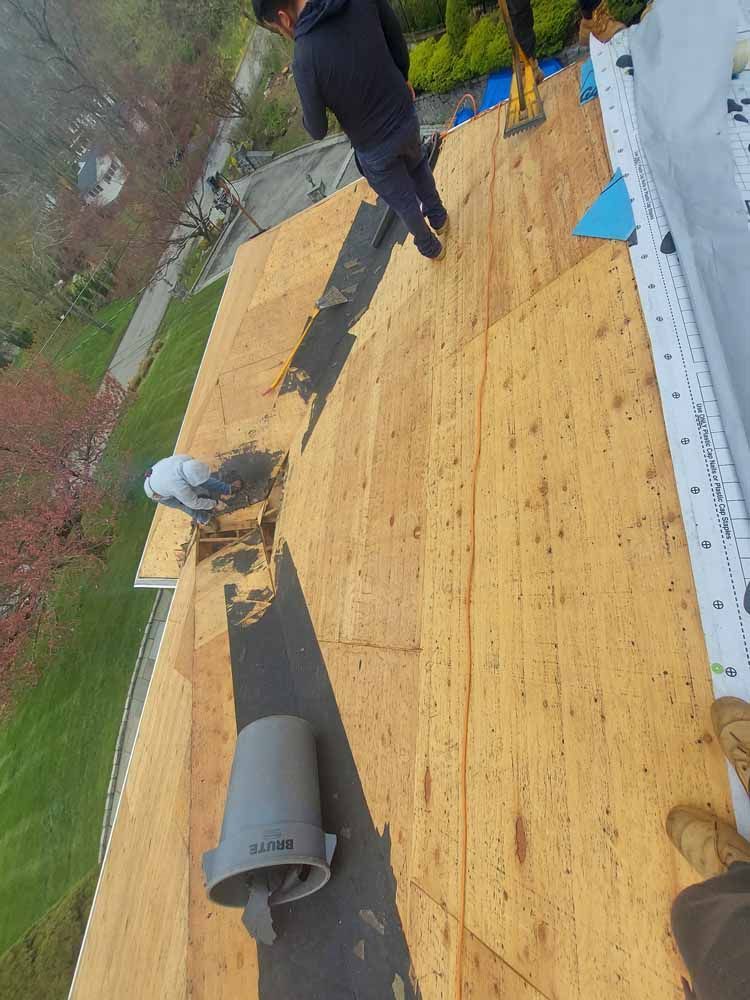 A man is standing on top of a wooden roof.