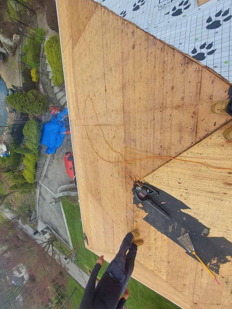 A person is standing on top of a wooden roof.