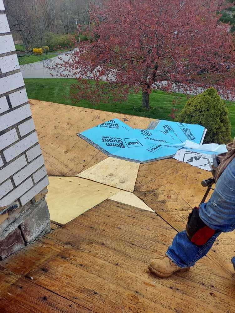 A person is standing on a wooden deck next to a brick building.