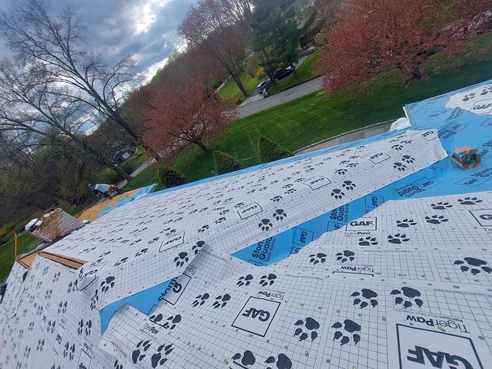 A roof is being covered with a blue and white roofing material.