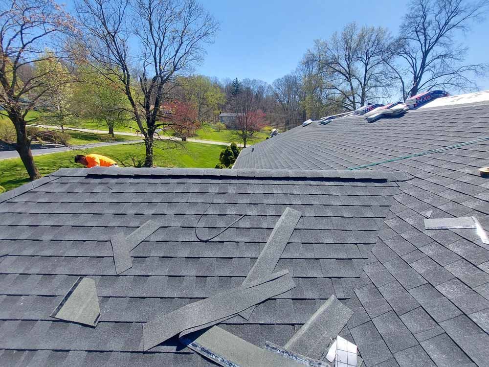 A roof with a lot of shingles on it and trees in the background.