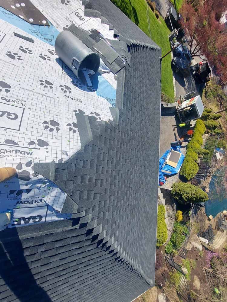 An aerial view of a roof with shingles being installed.