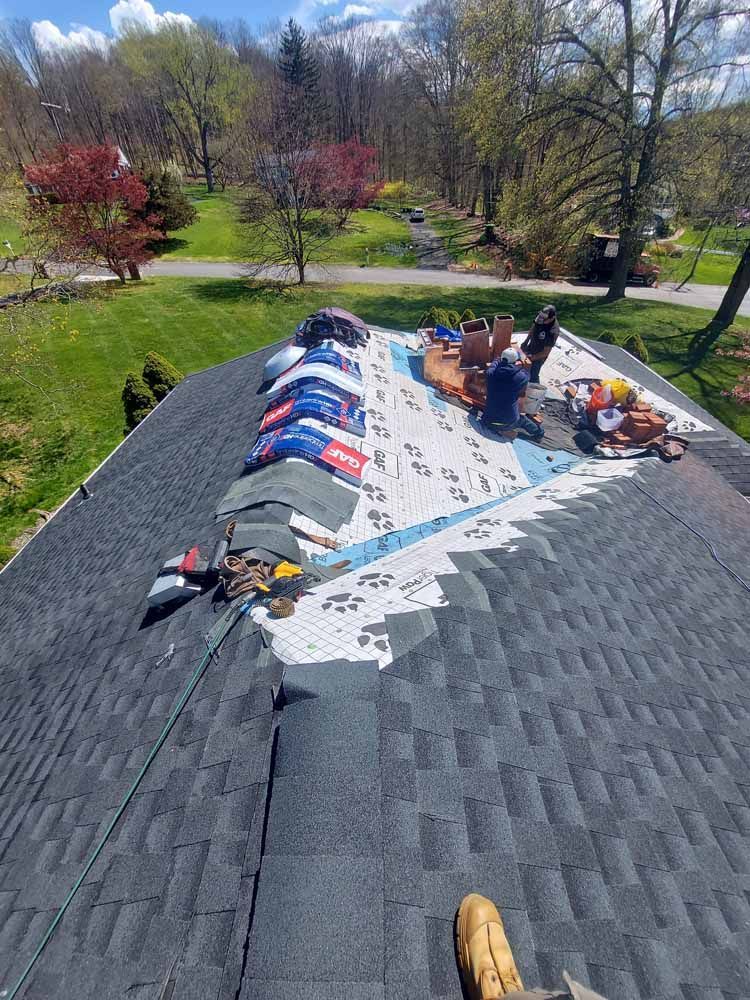 A group of people are working on the roof of a house.