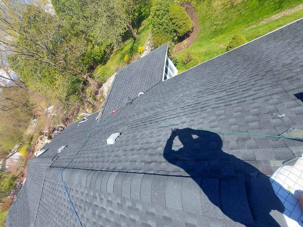 A person is standing on top of a roof with a shadow on it.