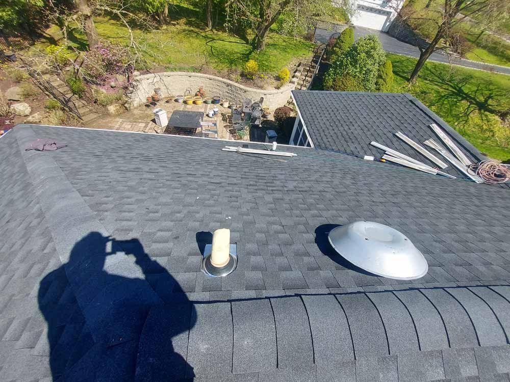 A man is standing on top of a roof taking a picture.