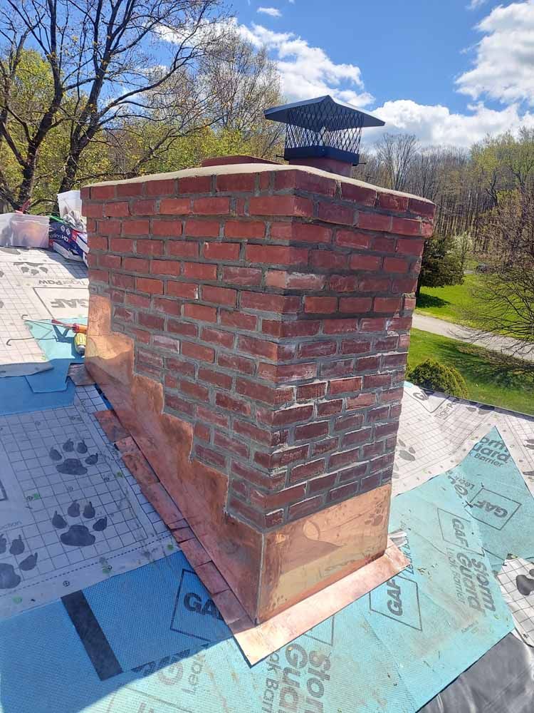 A brick chimney is sitting on top of a roof.