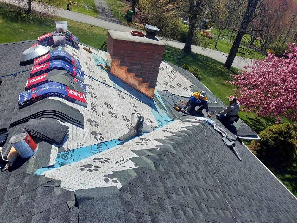 A group of people are working on the roof of a house.