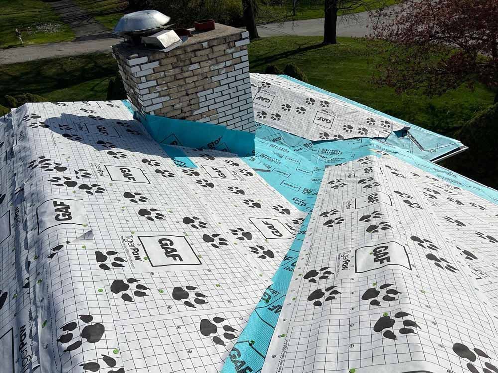 A roof with a chimney on top of it and a piece of paper with paw prints on it.