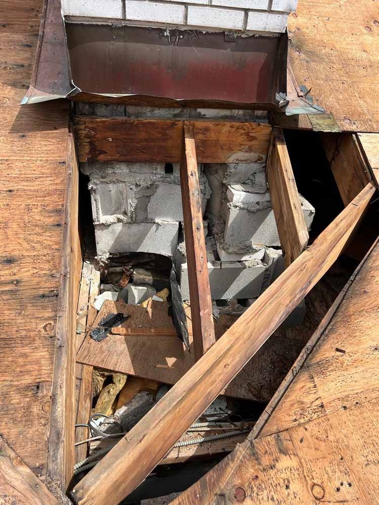 A hole in the roof of a building with a chimney coming out of it.