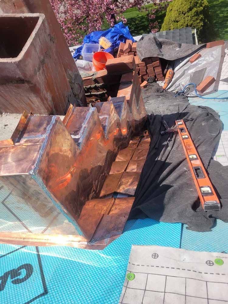 A copper chimney is being installed on a roof.