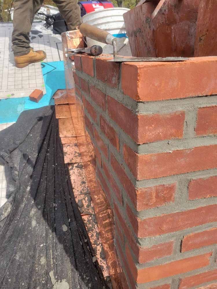 A man is laying bricks on a brick wall.