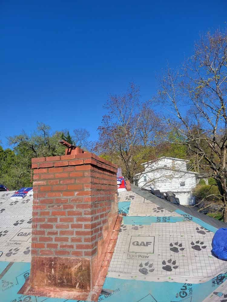 A brick chimney is sitting on top of a roof.