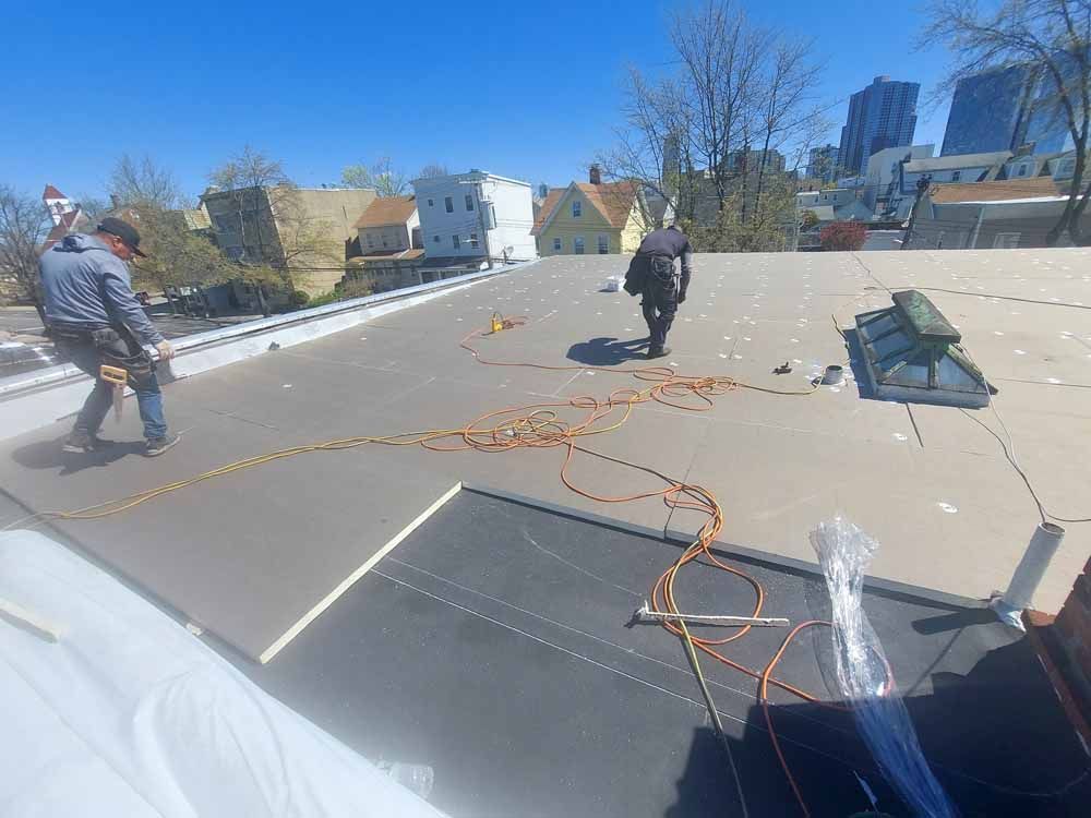 A couple of men are standing on top of a roof.