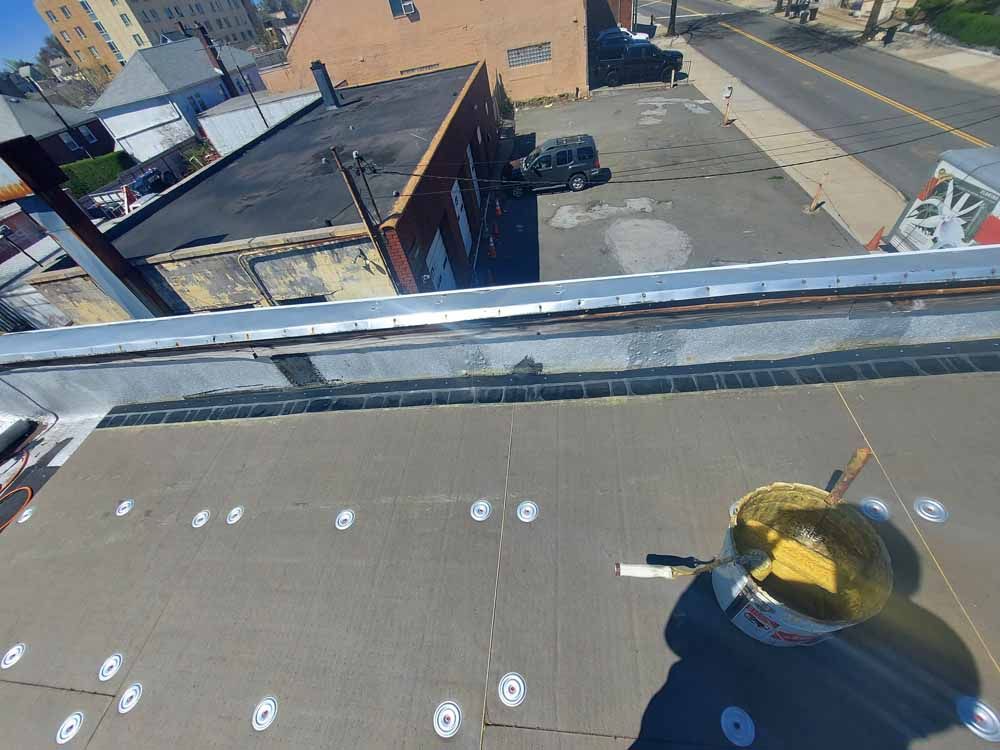 A bucket of yellow paint is sitting on the roof of a building.